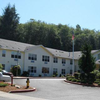 A residential building surrounded by trees and landscaping on a sunny day.