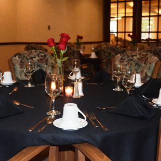 An elegantly set dining table adorned with red roses and glassware.