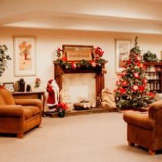 A cozy living room decorated for Christmas with a beautifully adorned tree and festive fireplace.