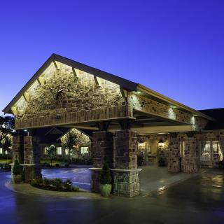 A stone building entrance illuminated by lights during the evening.