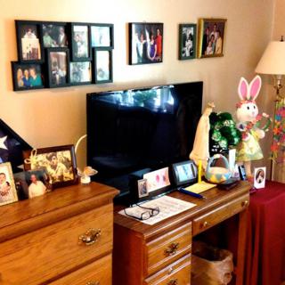 A cozy living room with a TV surrounded by family photos and decorations.