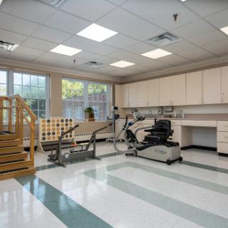 A spacious physical therapy room equipped with exercise equipment and a set of stairs for rehabilitation training.