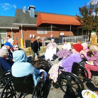 Elderly residents enjoying a sunny day outdoors at a care facility.