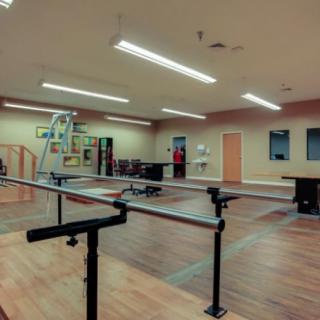 A rehabilitation center featuring parallel bars and various fitness equipment.
