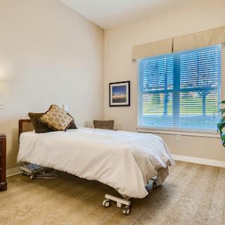 A serene bedroom setting featuring a neatly made bed, warm lighting, and a view of nature through the window.