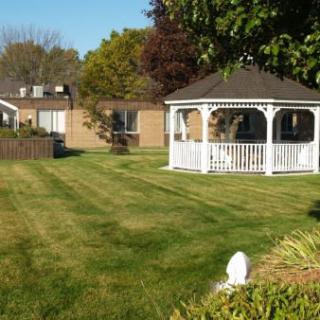A well-maintained lawn with a white gazebo and house in the background.