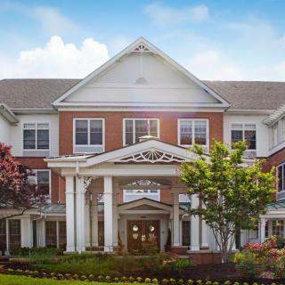 A large residential building with columns and landscaped surroundings under a blue sky.