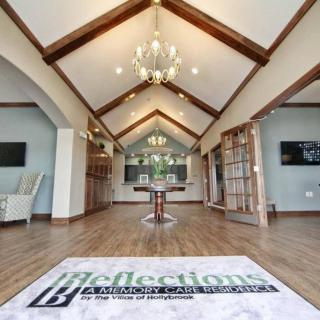 A spacious and elegantly designed interior with high wooden beam ceilings and a central chandelier.