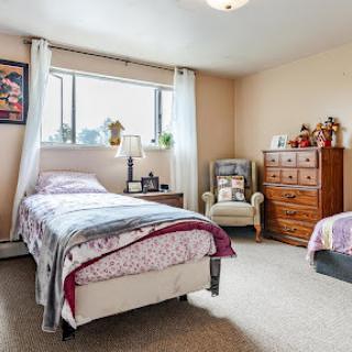 A cozy bedroom featuring two beds, a wooden dresser, and plenty of natural light.