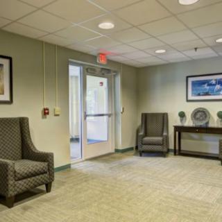 A well-lit lobby area featuring two armchairs, a console table, and framed artwork on the walls.