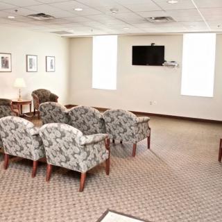 A well-lit waiting room with patterned chairs and a wall-mounted television.