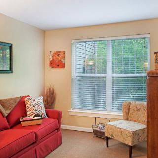 A cozy living room with a red sofa, an armchair, and a large window.