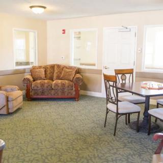 A cozy living room with a sofa, chairs, and a table on a green carpet.