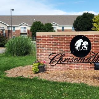 Brick entrance sign for a residential area with a building in the background.