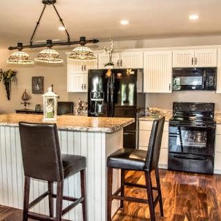 A stylish modern kitchen featuring sleek black appliances, elegant bar stools, and a beautiful granite countertop.