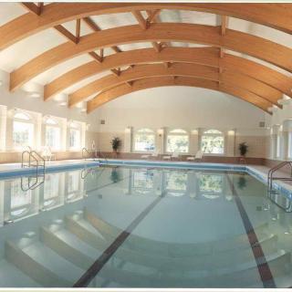 A spacious indoor swimming pool with wooden beams and large windows.