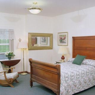 A cozy bedroom featuring a wooden bed, a decorative lamp, and a comfortable chair by the window.