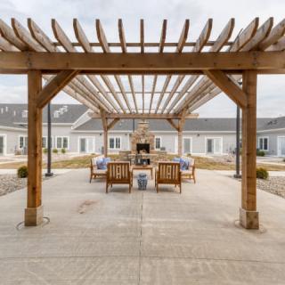 A well-designed outdoor courtyard features a wooden pergola with comfortable seating and a fireplace.