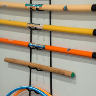 Various garden tools and brooms organized on a wall-mounted rack.