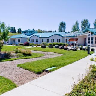 A serene view of a modern building surrounded by green lawns and walkways.