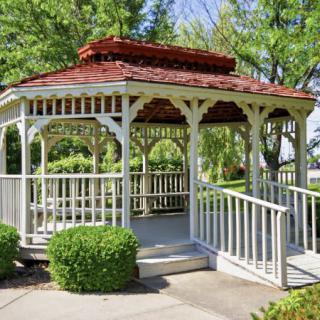 A charming wooden gazebo in a lush garden setting.
