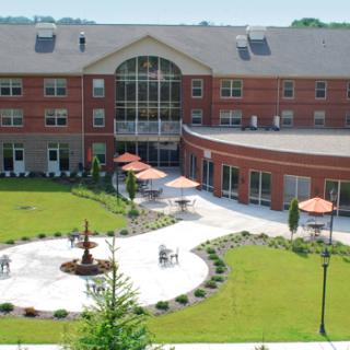 A well-maintained building with a central fountain, patio, and lush green lawn.