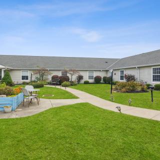 A well-maintained building with a green lawn and garden, featuring outdoor seating and a pathway.