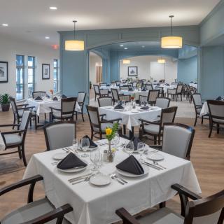 A spacious, elegantly set dining room with neatly arranged tables and chairs.