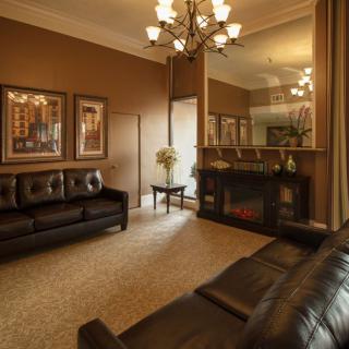 A cozy living room with leather sofas, elegant chandelier, and decorative elements.