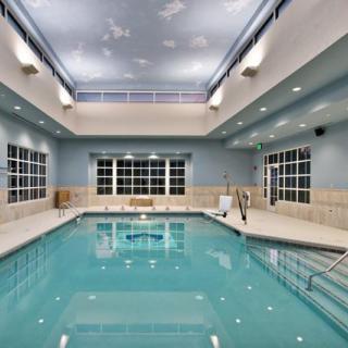 A well-lit indoor swimming pool with modern design elements and large windows.