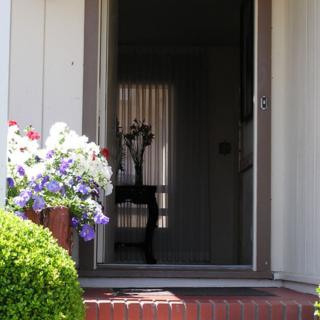 A welcoming home entrance with flowering plants and an open doorway leading inside.