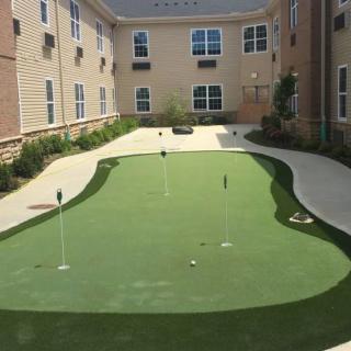 A well-maintained putting green located in the courtyard of an apartment complex.