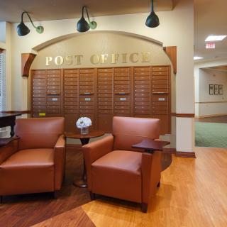 A cozy post office interior featuring lounge chairs and mailboxes.