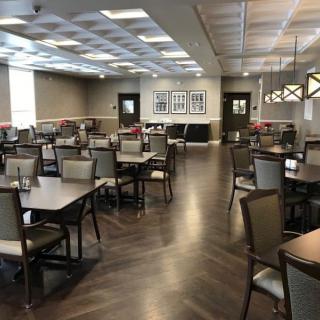 A spacious dining area with neatly arranged tables and chairs, featuring modern interior design and lighting.