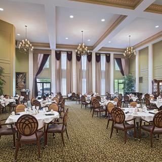 An elegant dining room with chandeliers and neatly arranged tables and chairs.