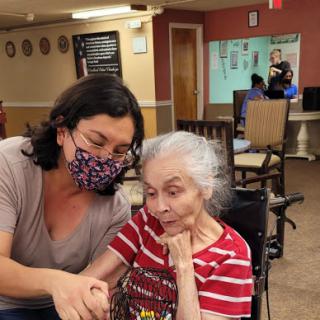 A caregiver attentively assists an elderly woman in a warm and supportive environment.