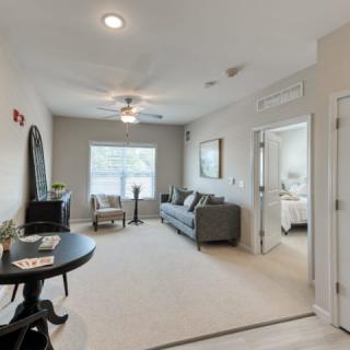 A modern living room with a sofa and table, featuring neutral colors and ample natural light.
