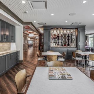 A modern dining area with stylish decor, featuring tables, chairs, and a bar section with decorative shelving.