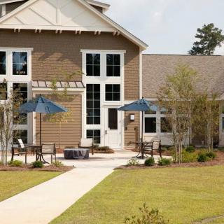 A residential building with a patio area featuring blue umbrellas and landscaping.