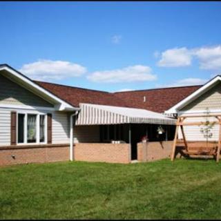 A charming residential home with a covered patio and a swing in the backyard.