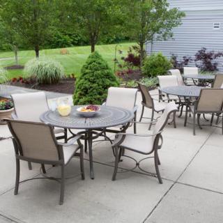 An outdoor patio setup with tables and chairs on a paved area surrounded by a garden.