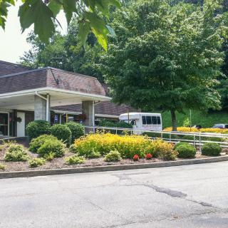 A landscaped area in front of a building with a parking lot and lush greenery.