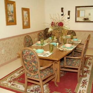 A traditional dining room with a wooden table set for six, featuring floral upholstered chairs and elegant decor.