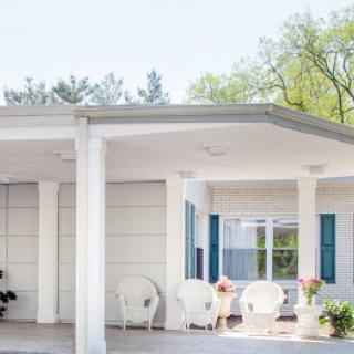 A serene outdoor porch featuring comfortable seating and blue shutters, perfect for enjoying nature.