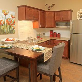 A cozy and modern kitchen with an adjacent dining area, featuring wooden cabinets and contemporary decor.