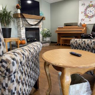 A cozy living room setting featuring patterned chairs, a wooden table, and a fireplace.