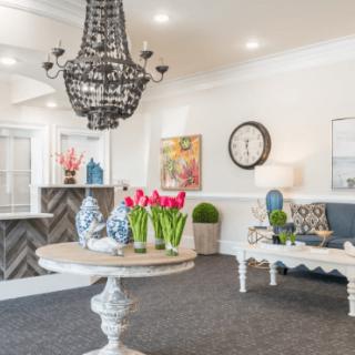 A stylish lobby with elegant decor, featuring a chandelier and fresh flowers on a round table.