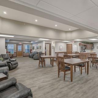 A spacious lounge area featuring multiple tables, chairs, and comfortable seating with modern lighting.