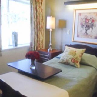 A cozy bedroom with a neatly made bed, bedside table, lamp, and wall art.