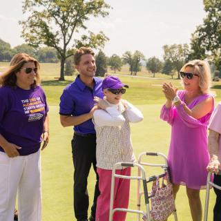 A group of people celebrating outdoors on a golf course during the day.